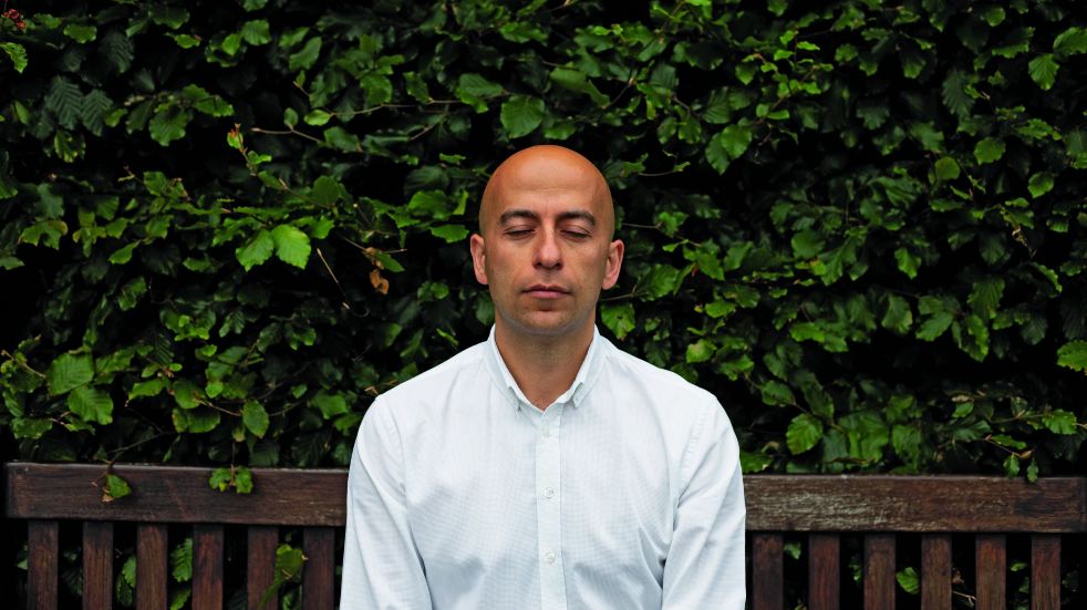 man meditating on bench outside